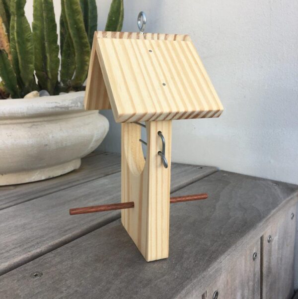 Side view of single fruit bird feeder next to plant